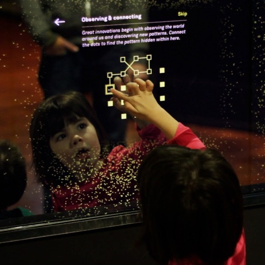 Visitors interacting with a touch-screen exhibit at the Bezos Center for Innovation at the Museum of History and Innovation